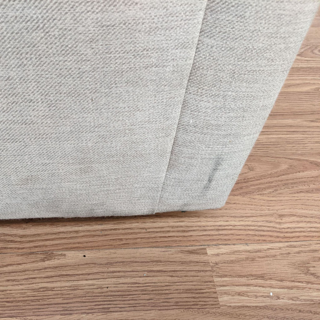 2. Close-up of a stained section of a Pottery Barn fabric armchair highlighting areas in need of cleaning against a wooden floor background.