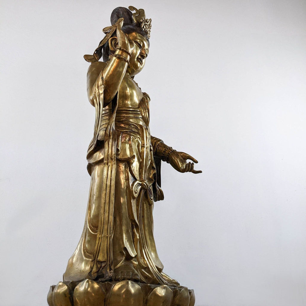 Side view of tall Chinese Reperch Guanyin sculpture, showing flowing robe details and open palm gesture.