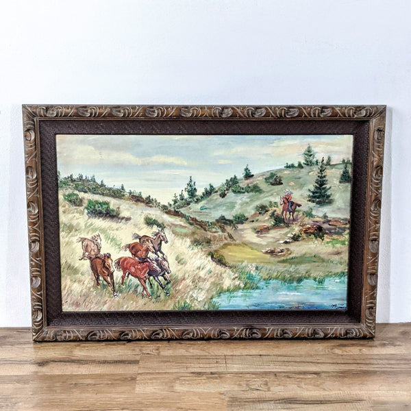 Framed painting of a cowboy and horses on a grassy hillside, with a stream in the foreground, by Sandy Huffaker.